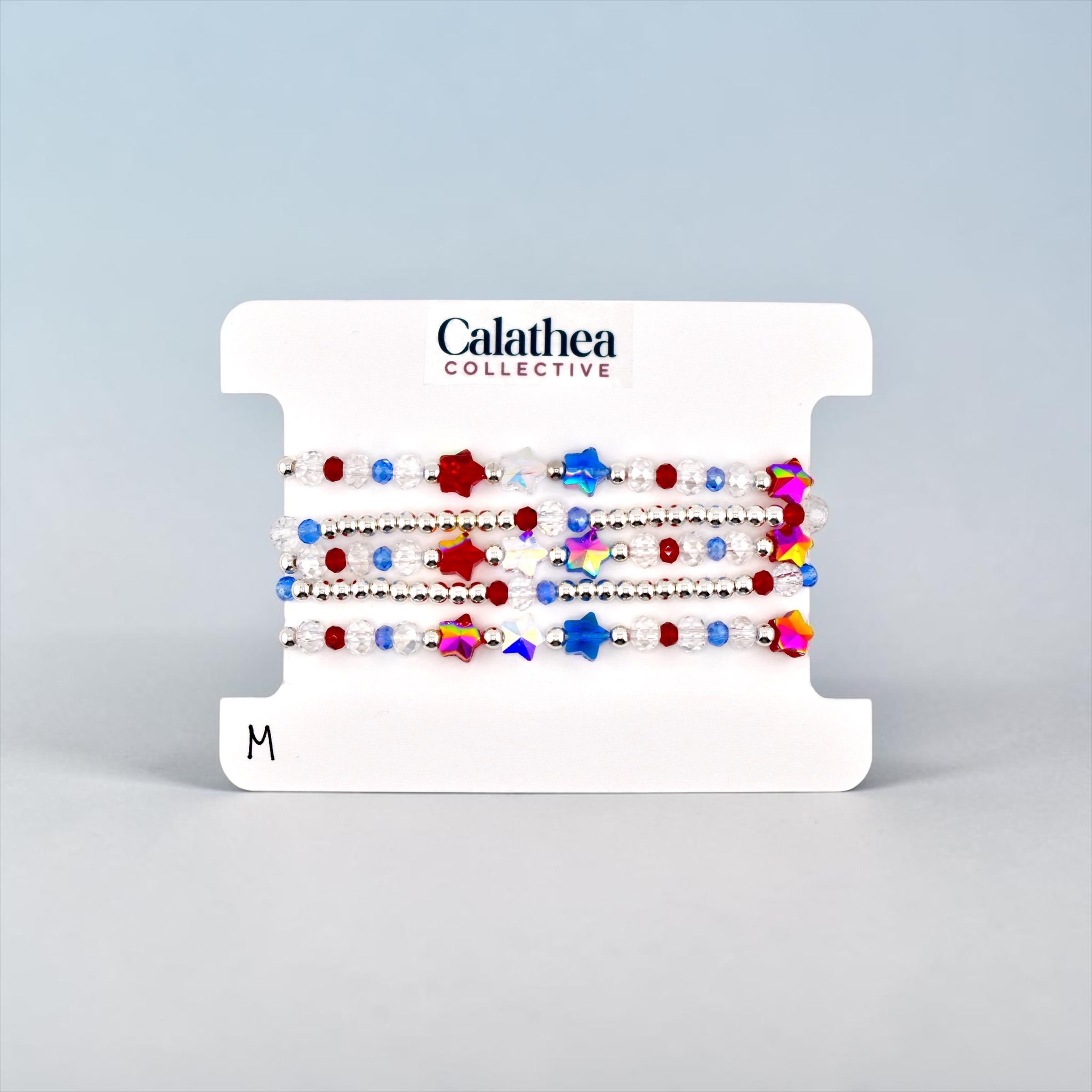 A set of beaded bracelets on a white card. The bracelets feature red, white, and blue beads, along with star-shaped beads in various colors.