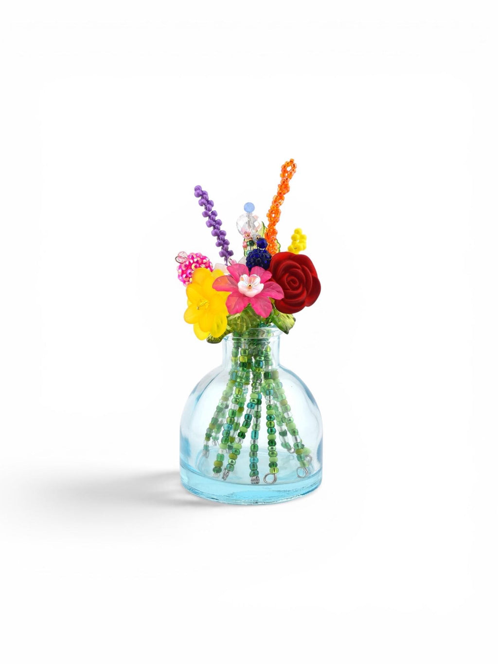 A small, clear light blue glass vase containing a bouquet of colorful beaded flowers. The stems are made of green beads, while the blossoms feature various shapes and vibrant colors including red, yellow, pink, purple, and orange.