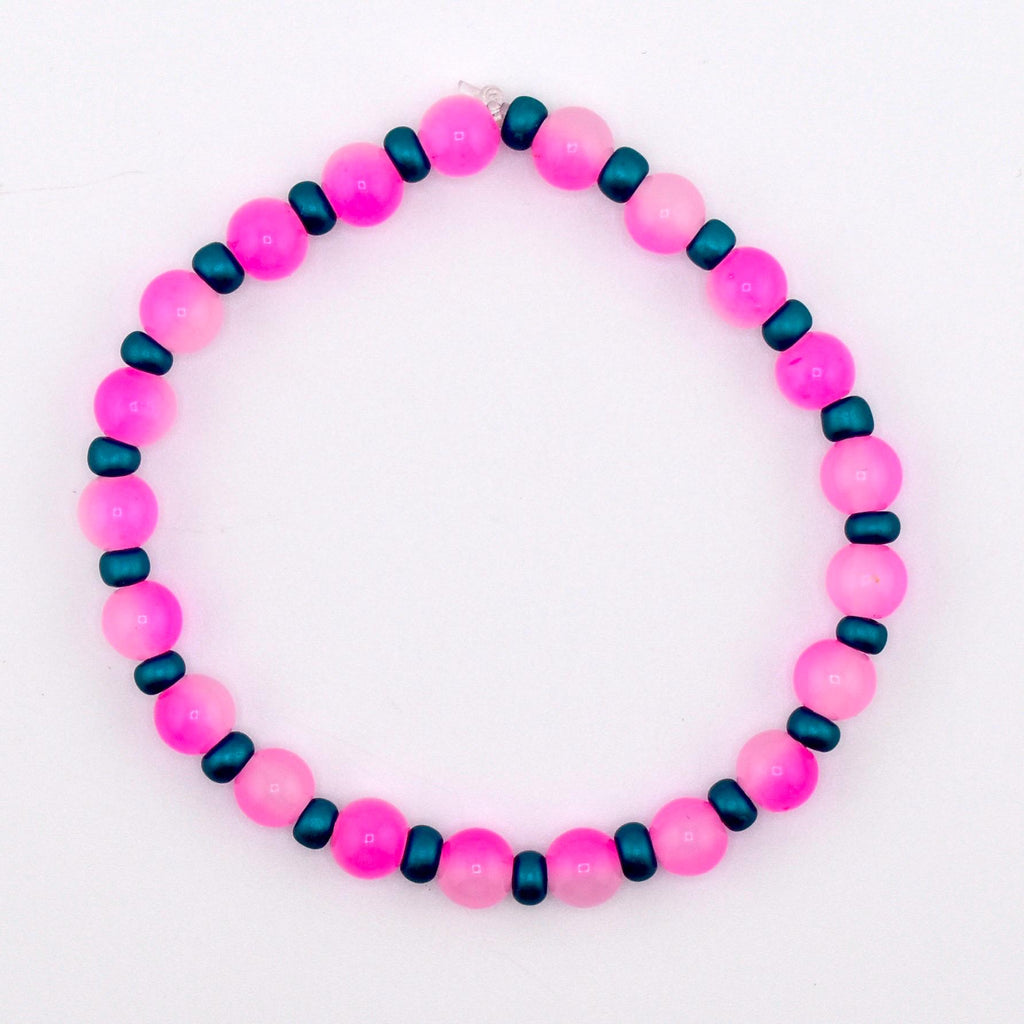 A beaded bracelet featuring alternating pink and teal beads. The pink beads are round and larger, while the teal beads are smaller and cylindrical. The bracelet is strung on stretchy clear string.