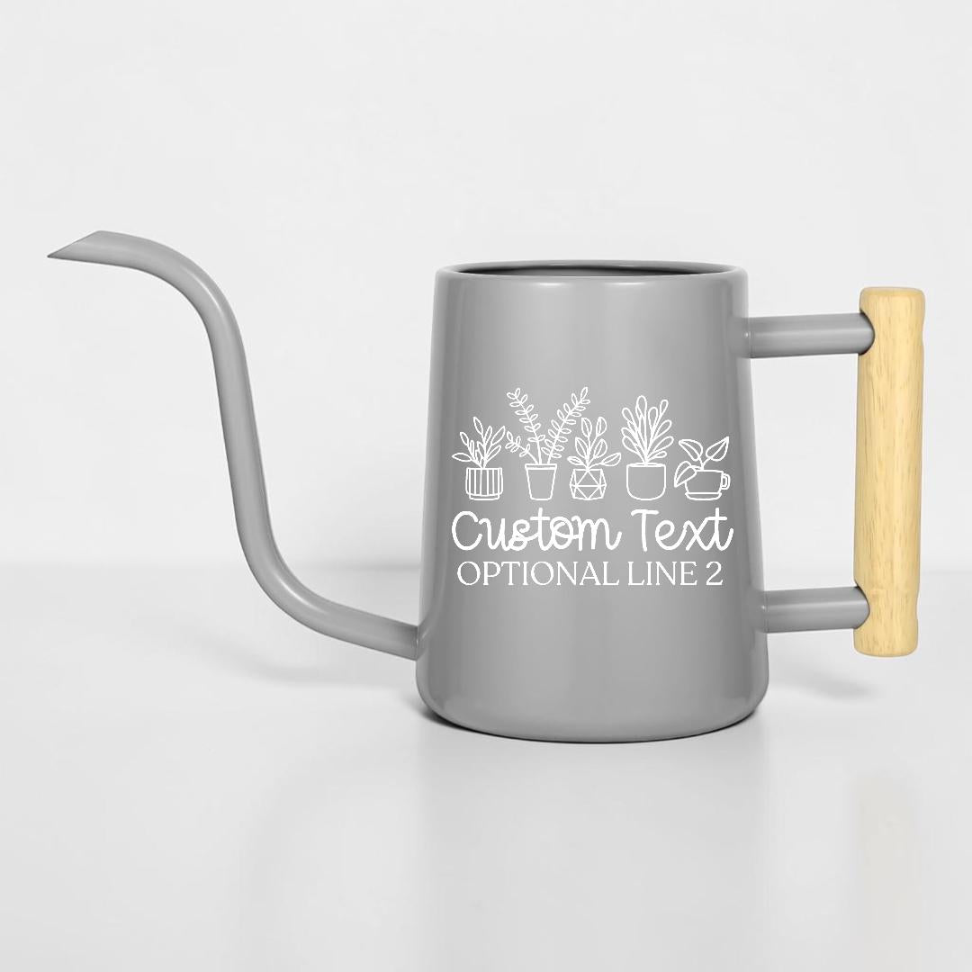 A gray metal watering can with a long, thin spout and a light-colored wooden handle. The side features a white line-art graphic of five potted plants above the white text "Custom Text" and "OPTIONAL LINE 2" in a script font.