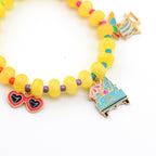 A beaded bracelet featuring yellow translucent beads interspersed with smaller purple, red, and teal beads. Charms include red heart-shaped sunglasses, a blue beach chair, and a blue truck with an umbrella and the text Hello Summer.