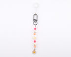 A beaded keychain featuring a silver-toned lobster clasp and a clear plastic loop. The strand includes alternating pink, peach, and white spherical beads, along with two white flower-shaped beads and a small white daisy charm at the end.