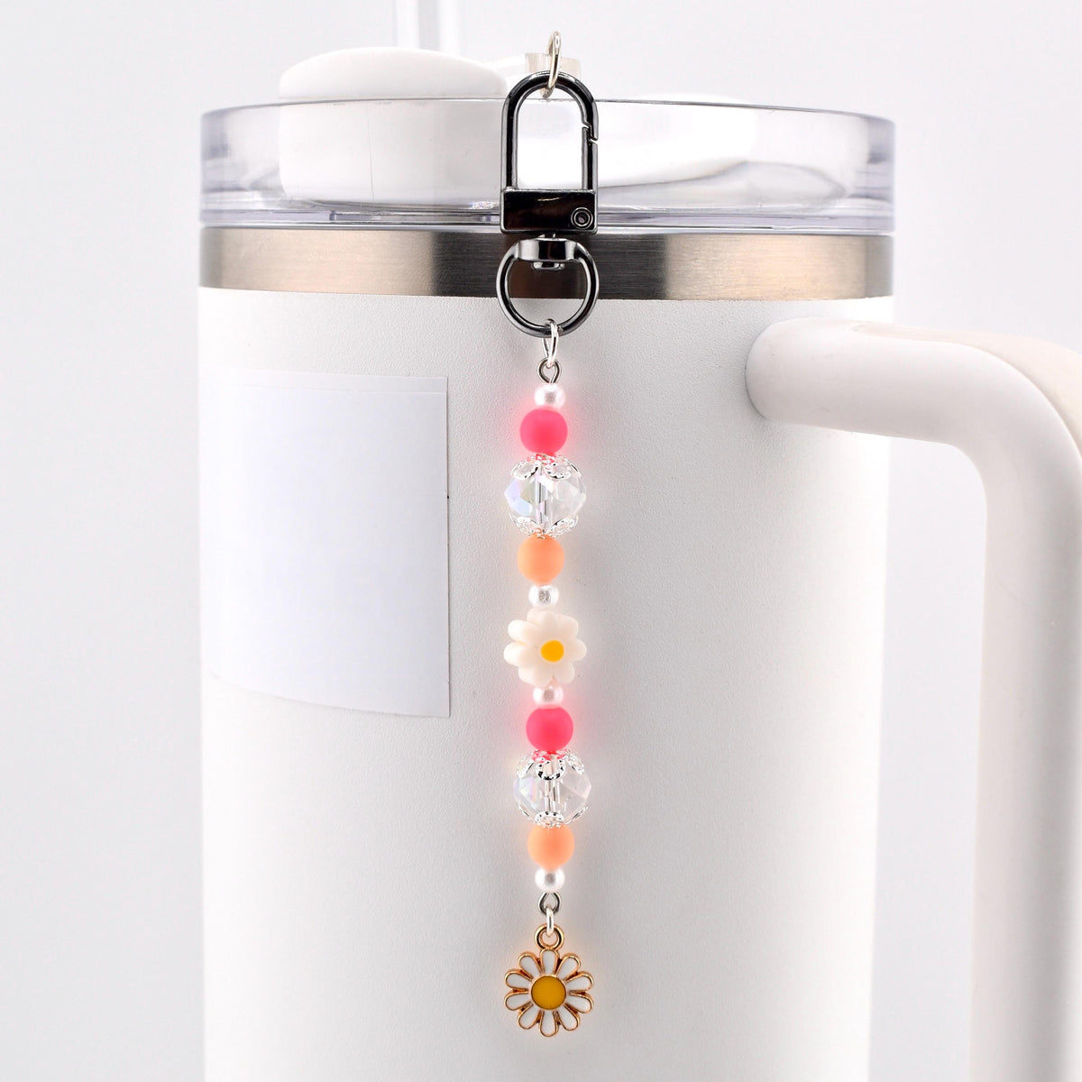 A beaded charm accessory featuring a silver-toned lobster clasp, pink and orange spherical beads, clear faceted beads, small white pearls, a white flower-shaped bead, and a gold-toned metal daisy charm with a yellow center.