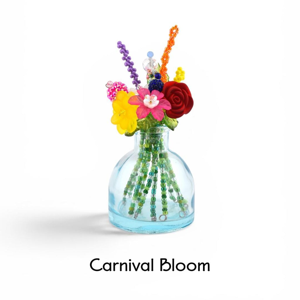 A small, clear light blue glass vase containing a bouquet of colorful beaded flowers and stems. The arrangement features red, yellow, and pink blossoms with purple and orange beaded accents. The text Carnival Bloom is below the vase.