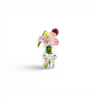 A miniature clear glass bottle containing a small bouquet of artificial flowers, including pink blossoms, green leaves, and a dark red textured sphere. The bottle is decorated with a white plastic bow attached to the front neck.