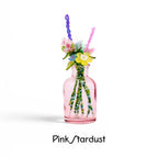 A small pink glass bottle containing a bouquet of artificial flowers made from colorful beads and plastic petals. The stems are crafted from green beads. The text Pink Stardust is printed in black below the bottle on a white background.