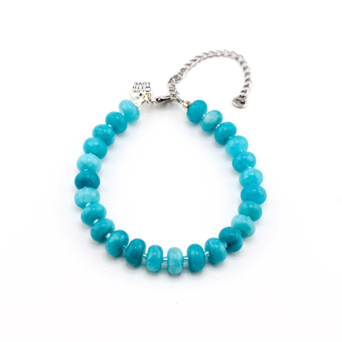 A bracelet featuring round, turquoise-colored beads with varying shades of blue and green. The bracelet includes a silver-toned metal chain extension and a small, rectangular silver charm engraved with the text MADE WITH LOVE.