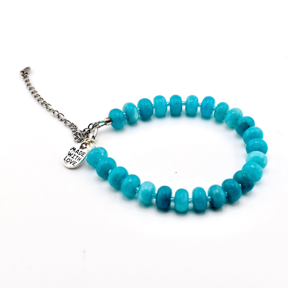 A bracelet featuring round, turquoise-colored beads with a smooth finish. The bracelet includes a silver-toned metal chain extension and a small, round silver-toned charm with the text MADE WITH LOVE engraved on its surface.