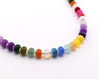 A necklace featuring a single strand of smooth, round, multi-colored beads in shades of purple, green, orange, blue, yellow, and pink, separated by small silver-toned spacers, arranged in a curved line against a plain white background.