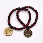 Two beaded bracelets featuring dark red and black marbled beads. One bracelet has a round brass-toned charm engraved with the text Always find the light. The other bracelet features a round brass-toned charm with a moth illustration.