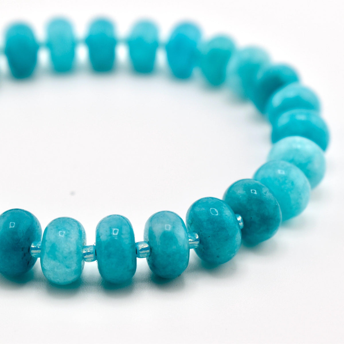 A bracelet composed of numerous round, disc-shaped beads in a vibrant turquoise blue color. The beads feature a smooth, polished finish with subtle variations in tone and texture, strung together in a circular arrangement.