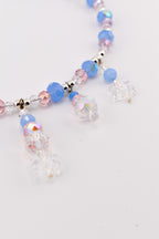 A beaded necklace featuring a strand of alternating light blue and pink faceted beads interspersed with small silver-toned spacers. Several dangling charms made of clear, iridescent, and blue beads hang from the main chain.
