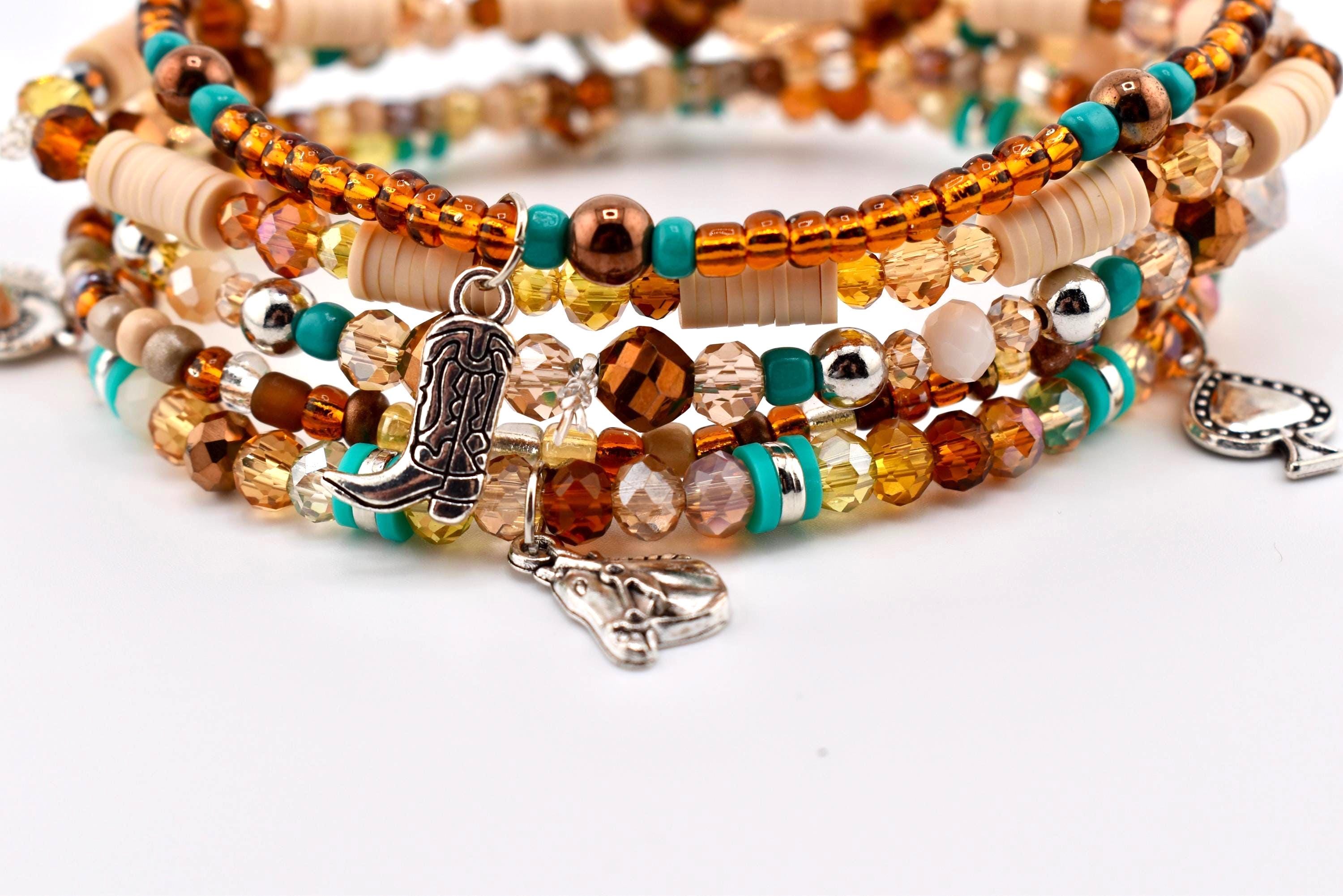 A multi-strand bracelet set featuring a mix of amber, brown, and turquoise beads, along with flat beige disc beads. The bracelet includes silver-toned metal charms shaped like a cowboy boot, a horse head, and a spade playing card.