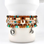 A multi-strand beaded bracelet featuring brown, turquoise, and cream-colored beads. The bracelet includes silver-toned charms shaped like a horseshoe, a cowboy hat, a cowboy boot, and a horse head, interspersed with faceted crystals.