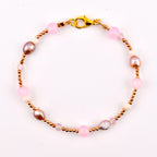 A beaded bracelet featuring a gold-tone lobster claw clasp, alternating between small metallic gold beads, smooth pink spherical beads, off-white round beads, faceted clear crystals, and irregular iridescent mauve-toned pearls.