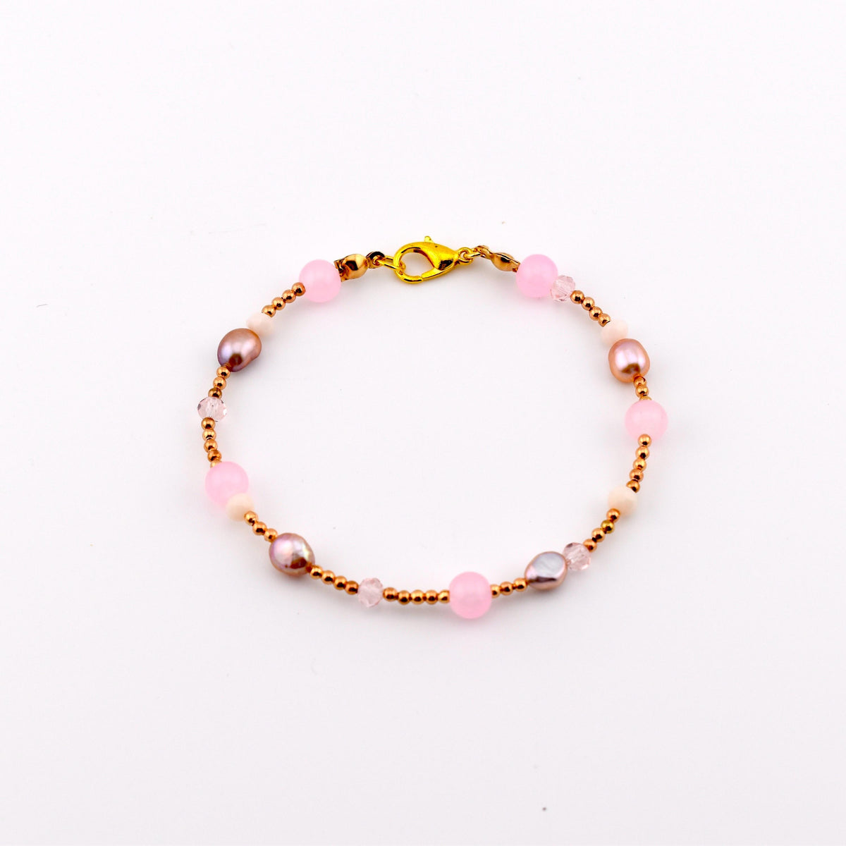A beaded bracelet featuring a gold-tone lobster claw clasp, alternating between small metallic gold beads, round translucent pink beads, and irregular-shaped iridescent brown pearls, arranged in a circular pattern on a white background.