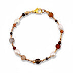 A beaded bracelet featuring a mix of white freshwater pearls, smooth brown stones, and small metallic gold-toned beads. The bracelet is secured with a gold-toned lobster claw clasp, creating a circular arrangement of varied textures.