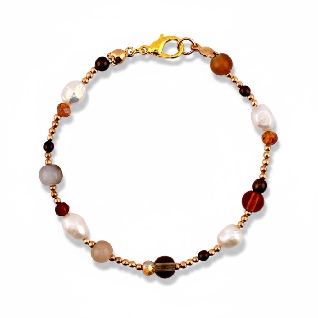 A beaded bracelet featuring a mix of white freshwater pearls, smooth brown stones, and small metallic gold-toned beads. The bracelet is secured with a gold-toned lobster claw clasp, creating a circular arrangement of varied textures.