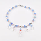 A beaded anklet featuring light blue and pale pink faceted beads, interspersed with small clear crystals. The piece includes five dangling charms, with three clear snowflake-shaped pendants and two round iridescent crystal beads.