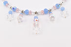 A necklace featuring a strand of light blue, pale pink, and clear faceted beads interspersed with silver-toned spacers. Five dangling charms, each composed of a clear snowflake-shaped bead and smaller round beads, hang from the main strand.