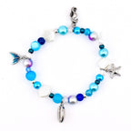 A beaded bracelet featuring a variety of blue, white, and iridescent beads interspersed with silver-toned charms including a seahorse, a starfish, a seashell, a cowrie shell, and a blue-enameled mermaid tail.