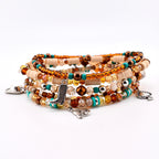 A stack of beaded bracelets featuring a mix of amber, brown, and turquoise glass beads, tan disc-shaped beads, and metallic accents. The bracelets include silver-toned charms shaped like a cowboy boot, a horse, and a spade.