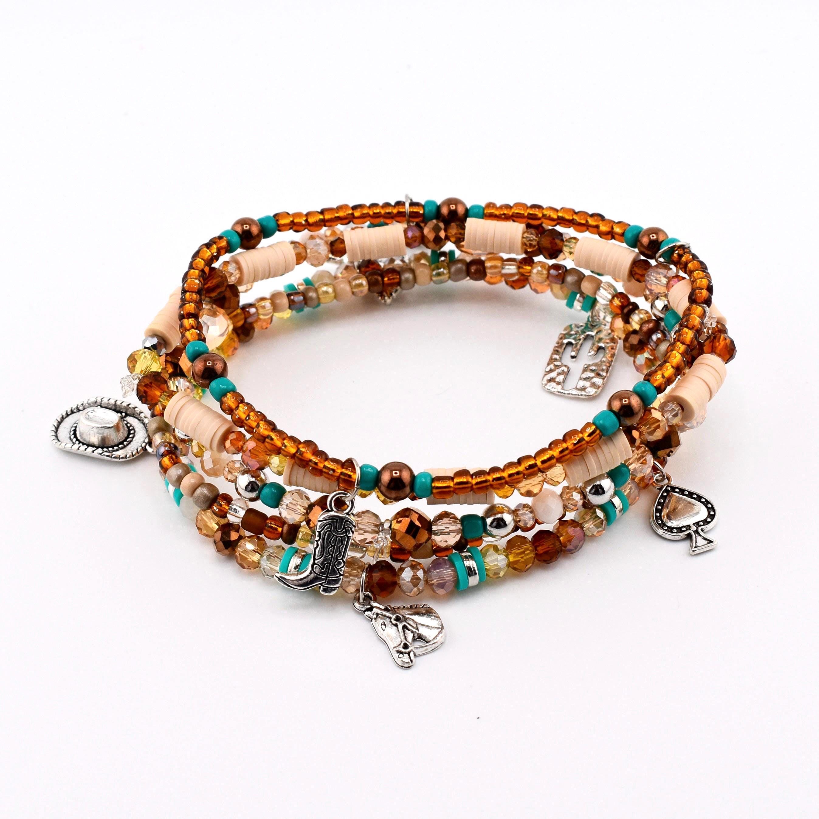 A multi-strand wrap bracelet featuring brown, turquoise, and beige beads with silver-toned charms. The charms include a cowboy hat, a cowboy boot, a horse head, a cactus, and a spade symbol, interspersed with faceted glass beads.