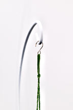 A thin, dark green braided cord featuring a small knot near the top, suspended from a metallic S-shaped hook that is attached to a curved white metal stand. The cord hangs vertically, showcasing its textured, woven fiber construction.