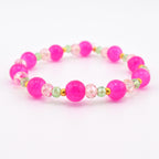 A beaded stretch bracelet featuring large, round, opaque hot pink beads alternating with smaller, faceted, translucent light pink and pale green beads, accented by tiny gold-toned metal spacers throughout the circular design.