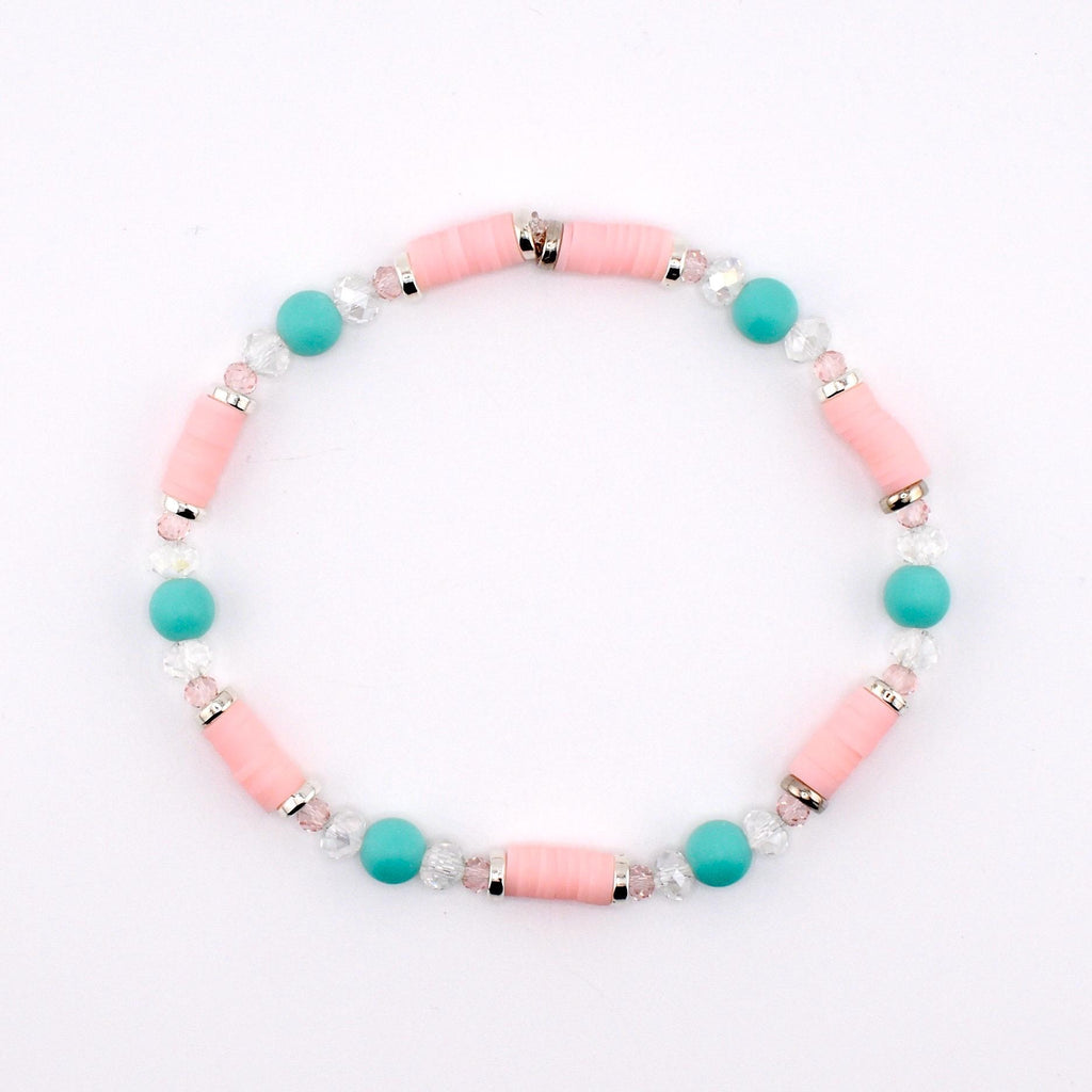 A beaded bracelet featuring cylindrical light pink clay beads, round turquoise beads, and small clear faceted crystal beads. The beads are arranged in a repeating pattern and separated by thin silver-toned metal spacers throughout the design.