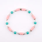 A beaded bracelet featuring cylindrical light pink clay beads, round turquoise beads, and small clear faceted crystal beads. The beads are arranged in a repeating pattern and separated by thin silver-toned metal spacers throughout the design.