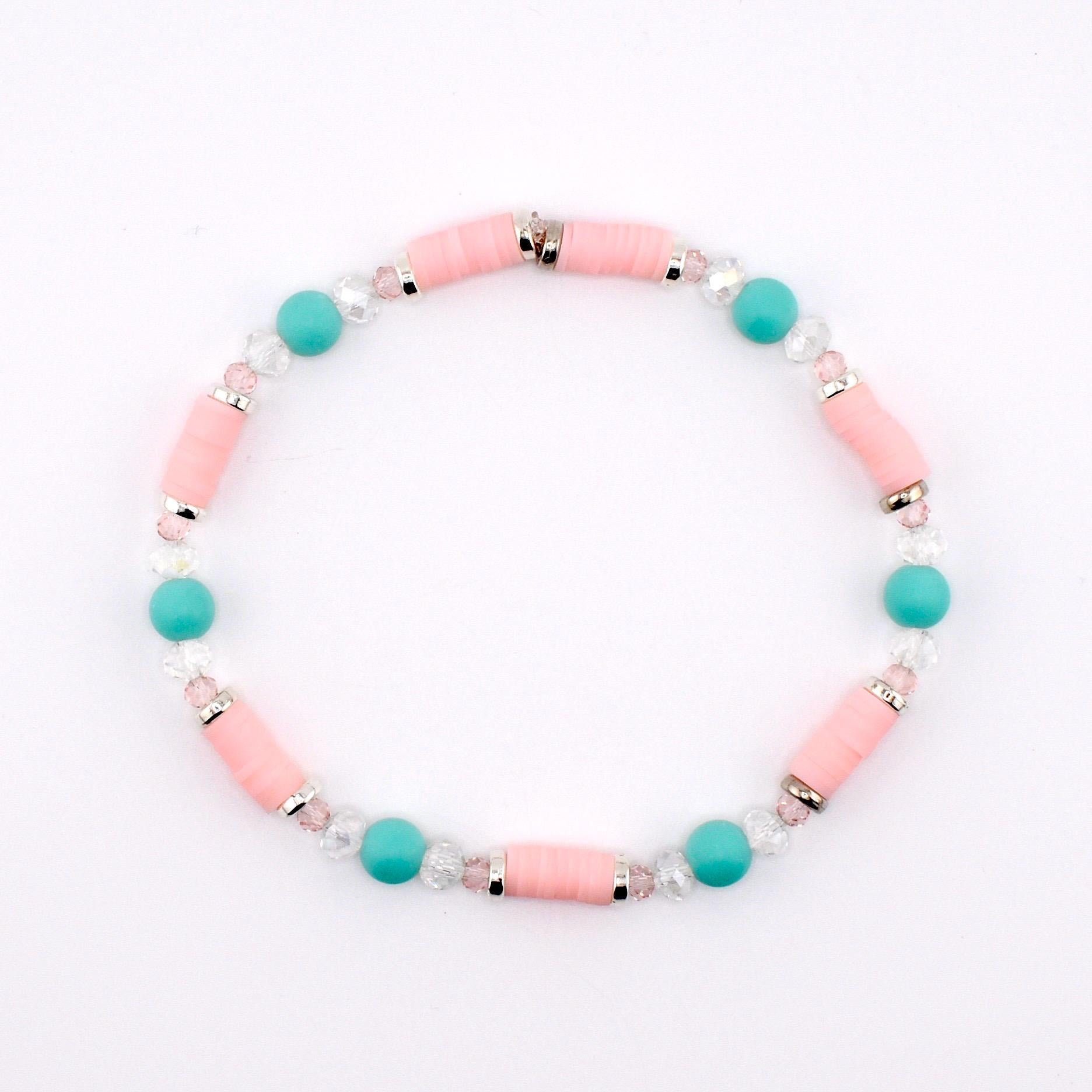 A beaded bracelet featuring cylindrical light pink clay beads, round turquoise beads, and small clear faceted crystal beads. The beads are arranged in a repeating pattern and separated by thin silver-toned metal spacers throughout the design.