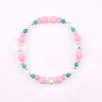 A circular beaded bracelet featuring a repeating pattern of matte pink round beads, small teal round beads, clear faceted crystal beads, and tiny white spacer beads arranged in a symmetrical design on a flexible elastic cord.