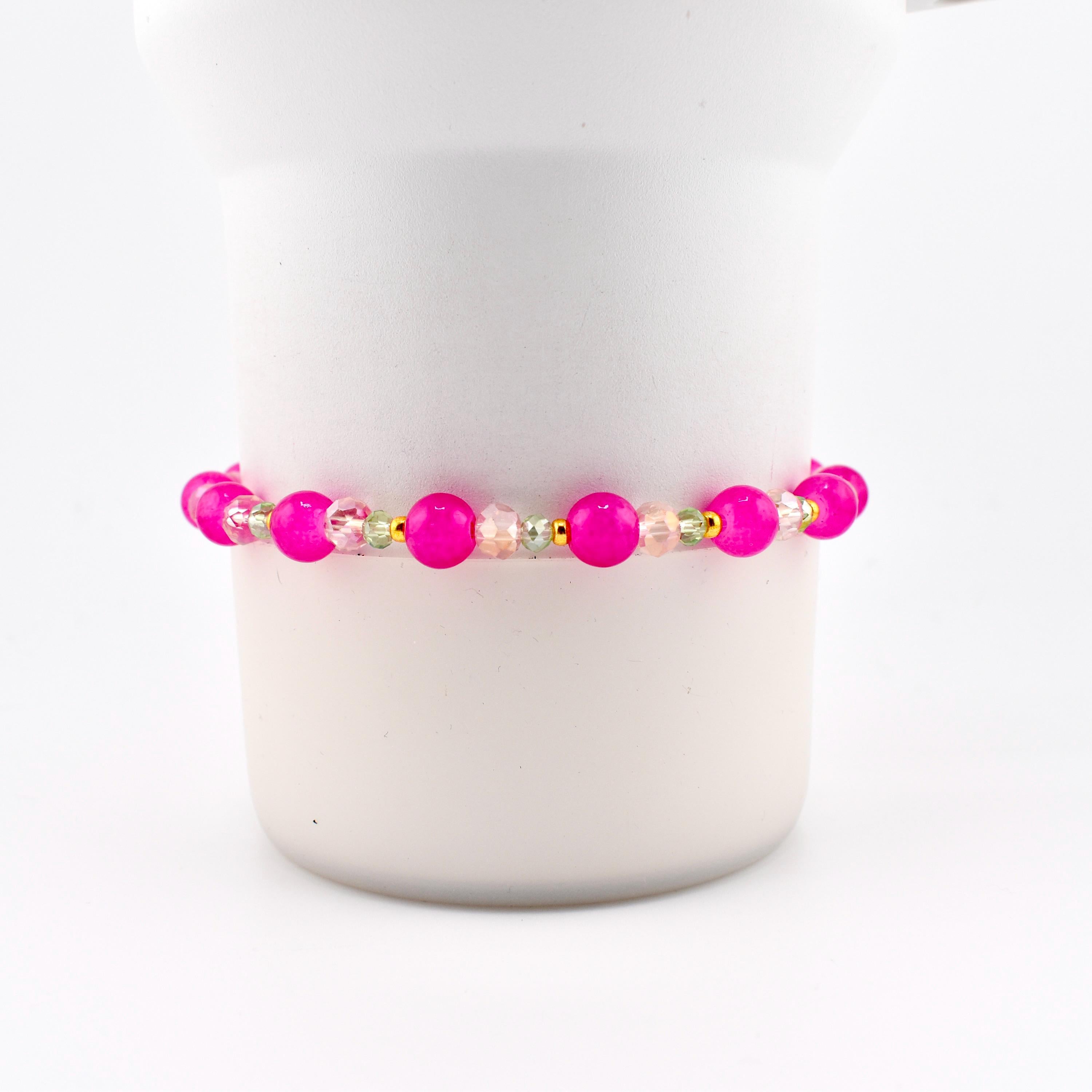 A beaded bracelet featuring vibrant hot pink round beads alternating with smaller, clear faceted crystal beads and tiny gold-toned metallic spacers. The design is symmetrical, showcasing a repeating pattern of pink and clear elements.