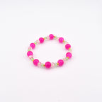 A circular beaded bracelet featuring alternating large round hot pink beads and smaller translucent light green faceted beads, accented with tiny gold-toned spacers arranged in a repeating pattern throughout the entire circular design.
