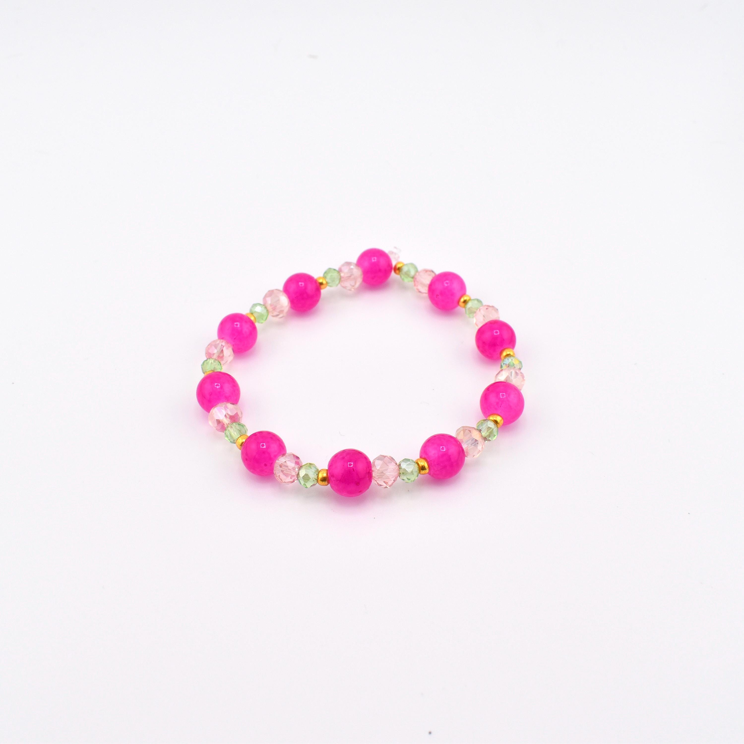 A circular beaded bracelet featuring alternating large round hot pink beads and smaller translucent light green faceted beads, accented with tiny gold-toned spacers arranged in a repeating pattern throughout the entire circular design.