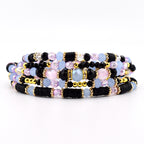 A multi-strand wrap bracelet featuring a combination of black disc-shaped beads, light blue faceted beads, pale pink round beads, and metallic gold spacers. The design incorporates clear crystal accents and small gold-toned metal beads.