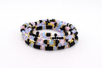 A multi-strand bracelet featuring a combination of black disc-shaped beads, light blue and pink faceted crystal beads, and small gold-toned metallic spacer beads arranged in a repeating pattern to create a layered appearance.