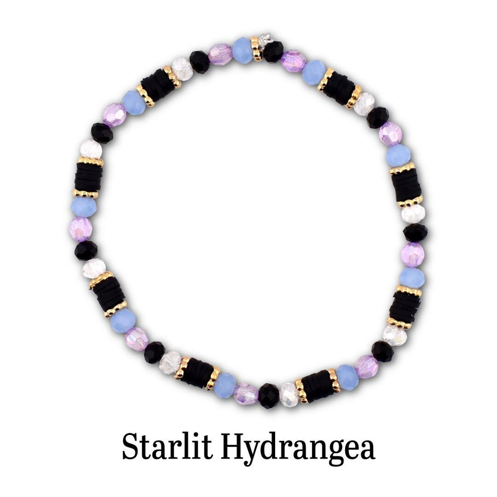 A circular beaded bracelet featuring alternating segments of black disc beads, light blue round beads, faceted lavender beads, and white beads, accented with small gold-toned spacers. The text Starlit Hydrangea is printed below.