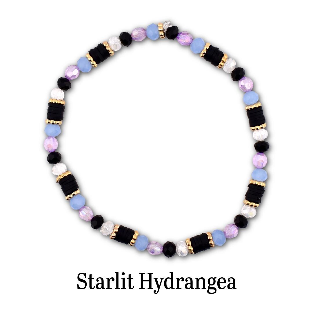 A circular beaded bracelet featuring alternating segments of black disc beads, light blue round beads, faceted lavender beads, and white beads, accented with small gold-toned spacers. The text Starlit Hydrangea is printed below.