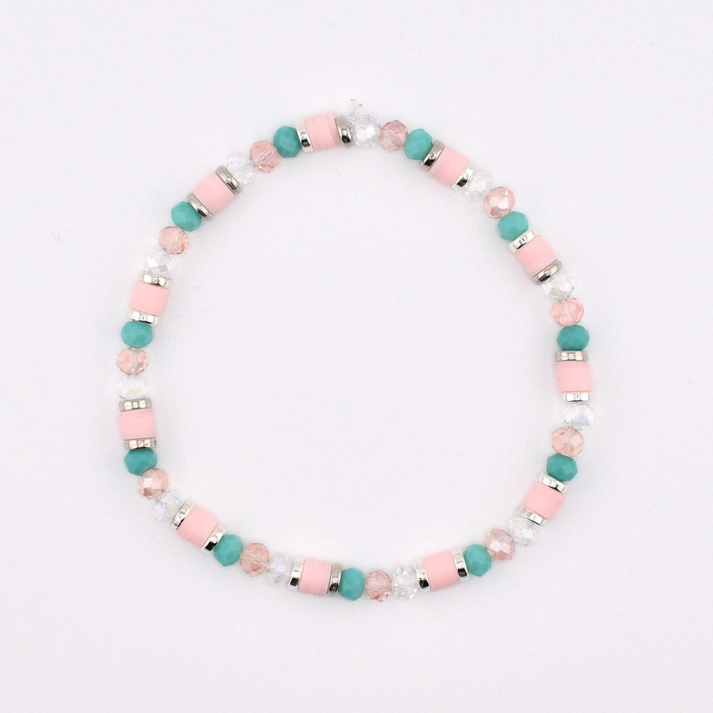 A beaded bracelet featuring a repeating pattern of cylindrical light pink beads, round turquoise beads, faceted clear crystal beads, and small silver-toned metal spacers arranged in a circular design on a plain white background.