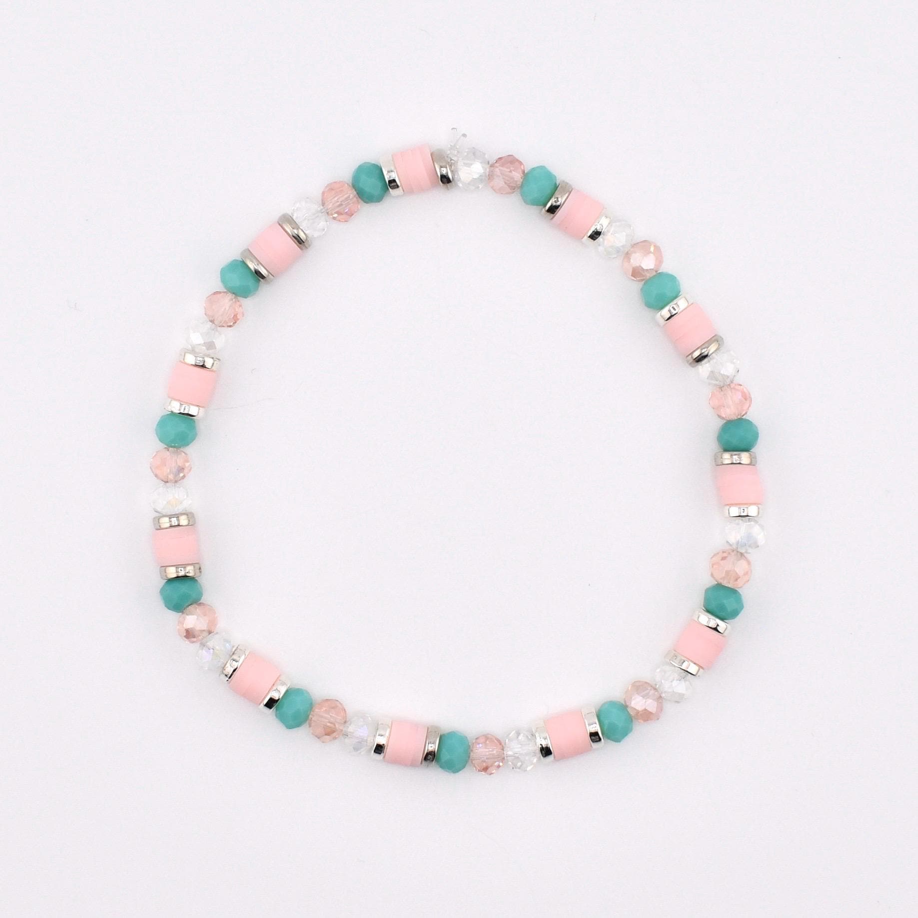 A beaded bracelet featuring a repeating pattern of cylindrical light pink beads, round turquoise beads, faceted clear crystal beads, and small silver-toned metal spacers arranged in a circular design on a plain white background.