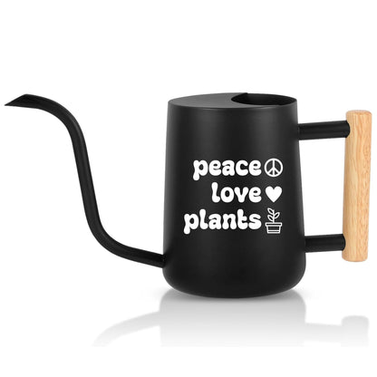 Black watering can with 'peace love plants' text and heart symbol on a white background