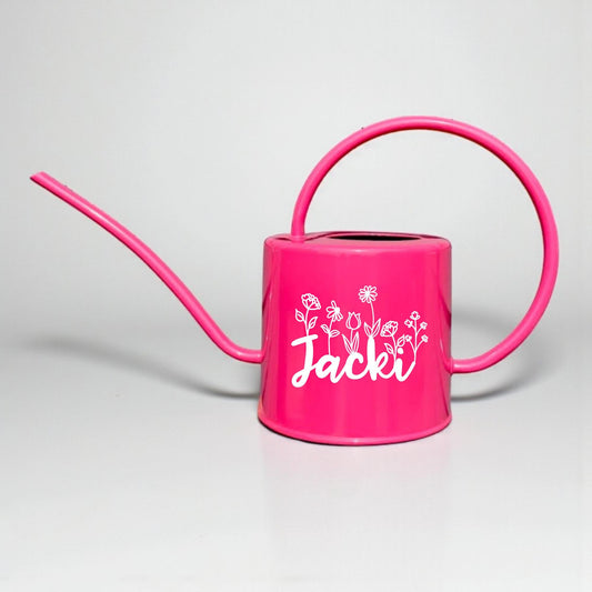 Pink watering can with a name and floral designs on a light gray background