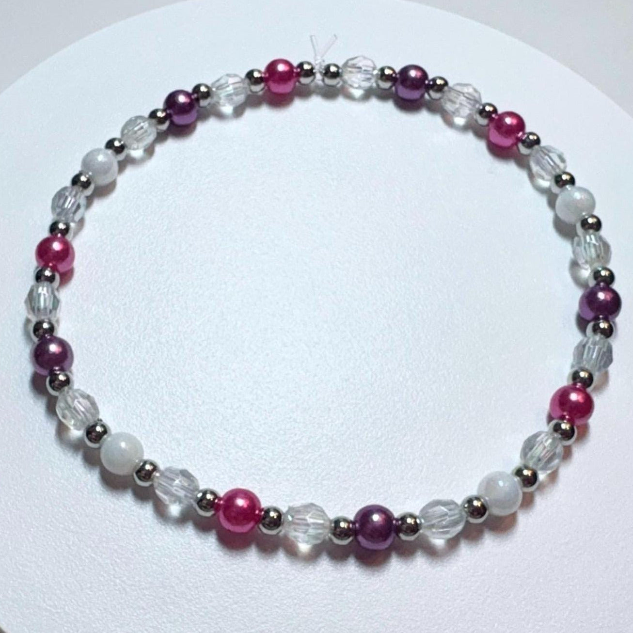 Beaded bracelet with pink and purple beads on a white background