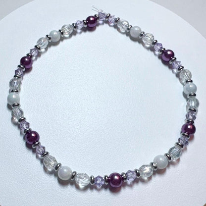 Beaded bracelet with purple and clear beads on a white background