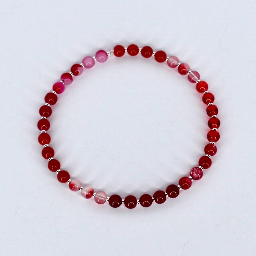 Beaded bracelet with red and pink beads on a white background