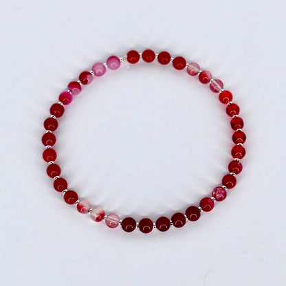 Beaded bracelet with red and pink beads on a white background